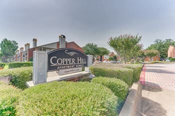 A sign for Copper Hill Apartment Homes is in front of a building.